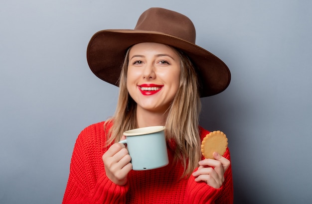 Donna in maglione rosso e tazza con biscotto