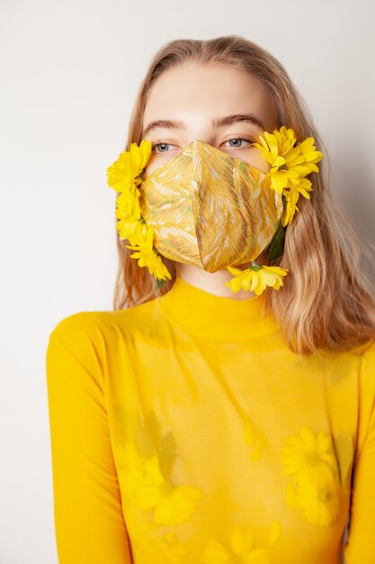 Donna in maschera con fiori gialli in studio