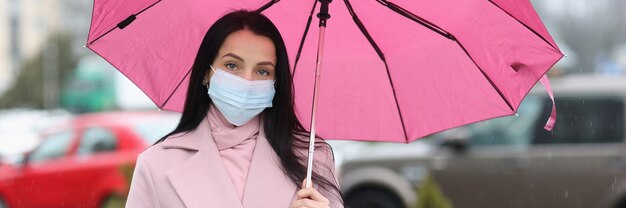 Donna in maschera medica protettiva con ombrello in mano nuova realtà durante la pandemia di covid