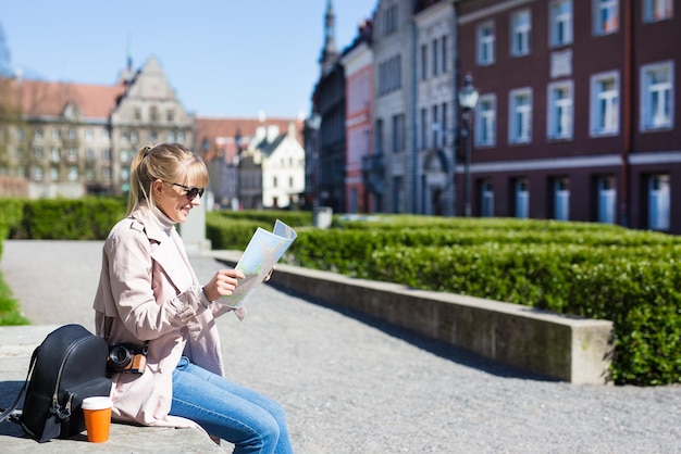 donna in occhiali da sole con mappa zaino e macchina fotografica nella città vecchia di Tallinn Estonia