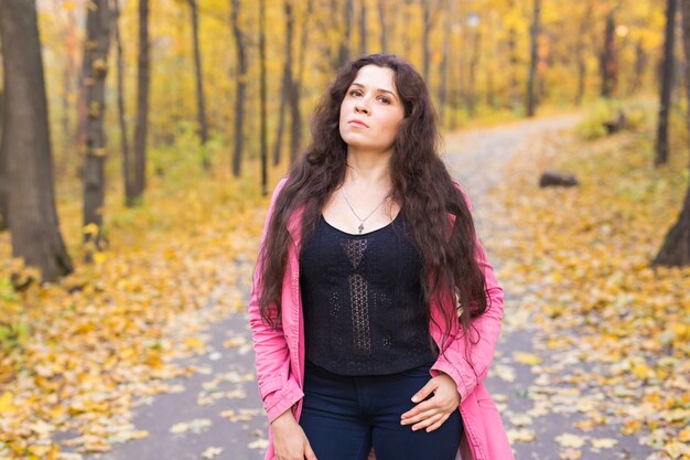 Donna in pantaloni blu e giacca rosa in piedi nella foresta di autunno