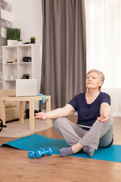 Donna in pensione che si rilassa nel soggiorno sul tappetino da yoga