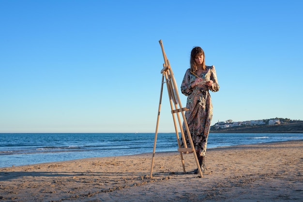 Donna in piedi accanto a Easel sulla spiaggia