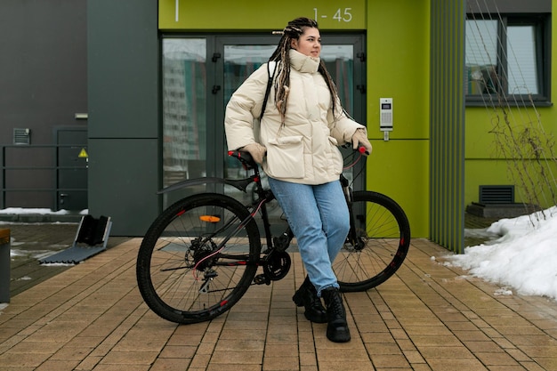 Donna in piedi accanto alla bicicletta davanti all'edificio
