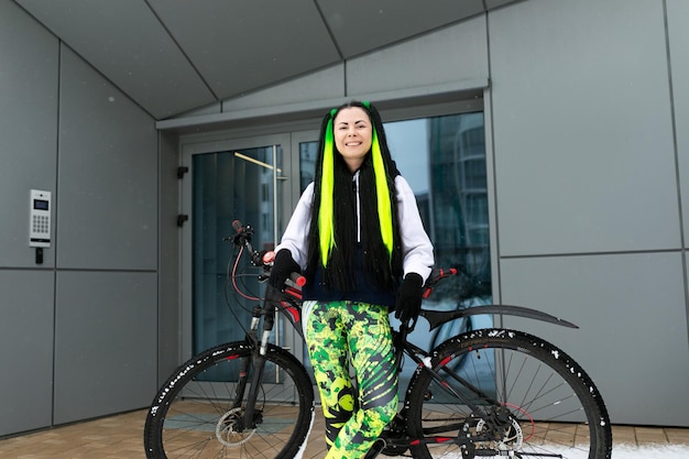 Donna in piedi accanto alla bicicletta davanti all'edificio