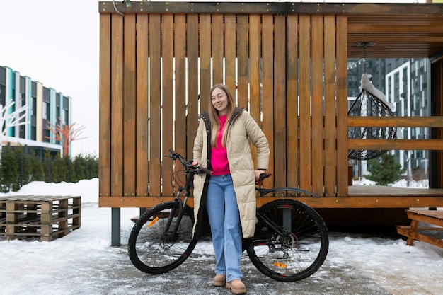 Donna in piedi accanto alla bicicletta nella neve