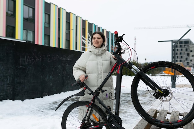 Donna in piedi accanto alla bicicletta nella neve