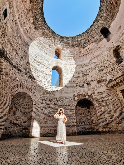 Donna in piedi all'interno di un antico edificio romano con luce naturale che risplende su di lui attraverso il tetto circolare