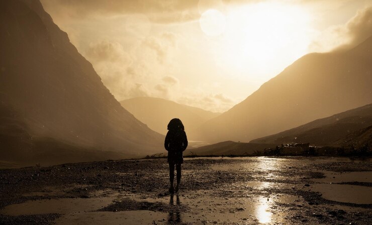 Foto donna in piedi contro le montagne durante il tramonto