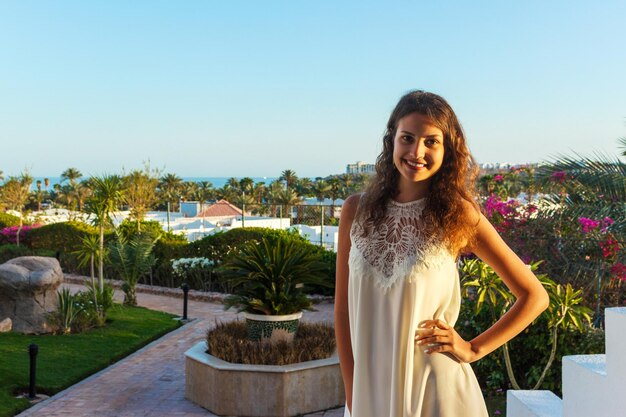 Donna in piedi nel parco Bella giovane donna sorridente su uno sfondo di palme e mare