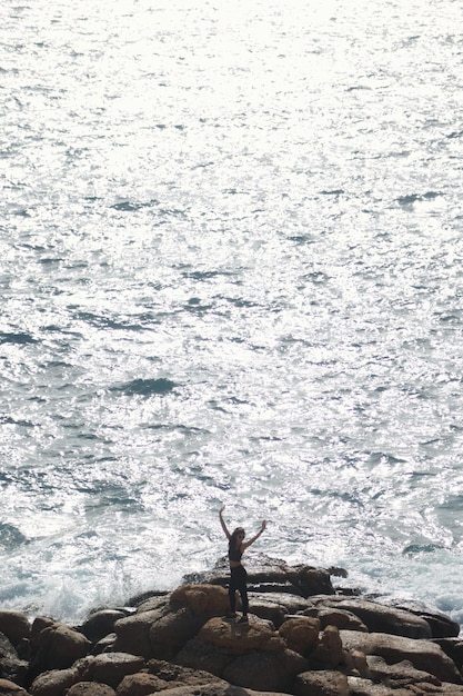 Donna in piedi su una roccia vicino al mare