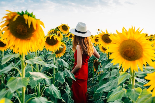 Donna in piedi sul campo di girasoli contro il cielo