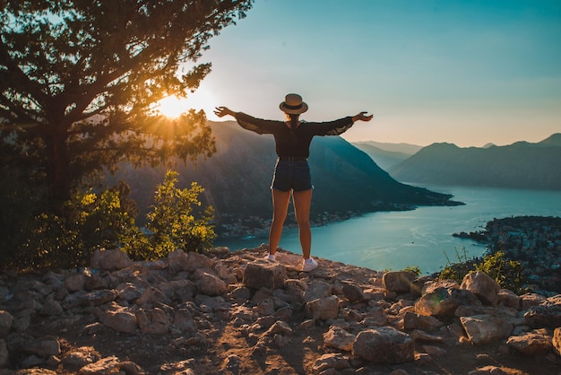 Donna in piedi sulla cima della collina di Cattaro con il tramonto sullo sfondo