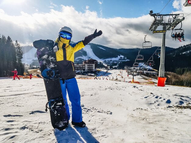 Donna in piedi sulla collina della stazione sciistica con attività ricreative invernali di snowboard