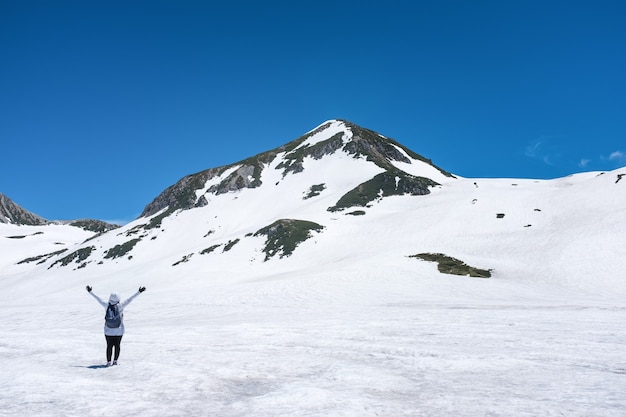 Donna in piedi sulla montagna di neve con cielo blu