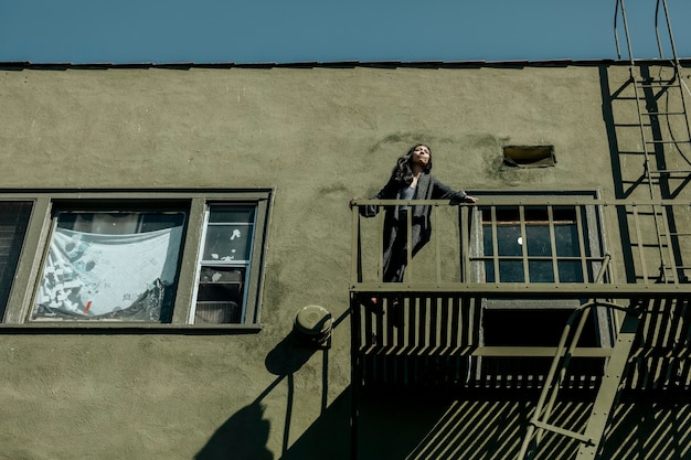 Donna in piedi sulla scala antincendio del suo appartamento nel centro di Los Angeles durante la pandemia di covid-19.