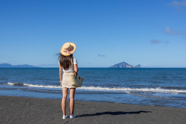 Donna in piedi sulla spiaggia a guardare l'isola