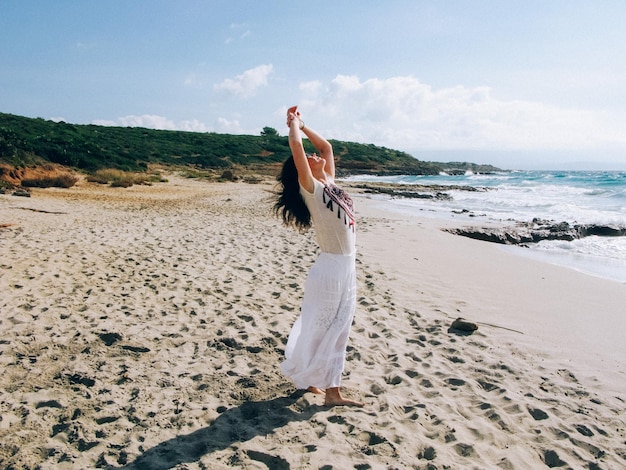 Donna in piedi sulla spiaggia contro il cielo