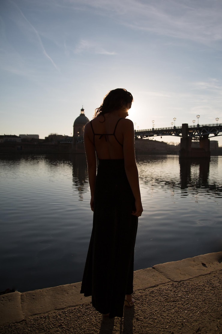 Foto donna in piedi vicino al lago al tramonto
