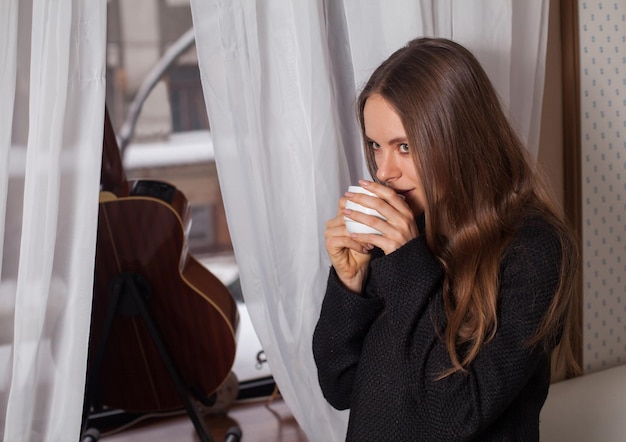 Donna in piedi vicino alla finestra e bere caffè