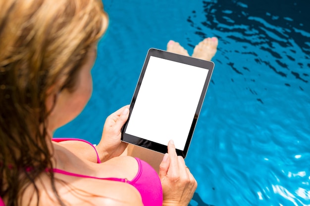 Donna in piscina che tiene tablet verticalmente con schermo bianco vuoto