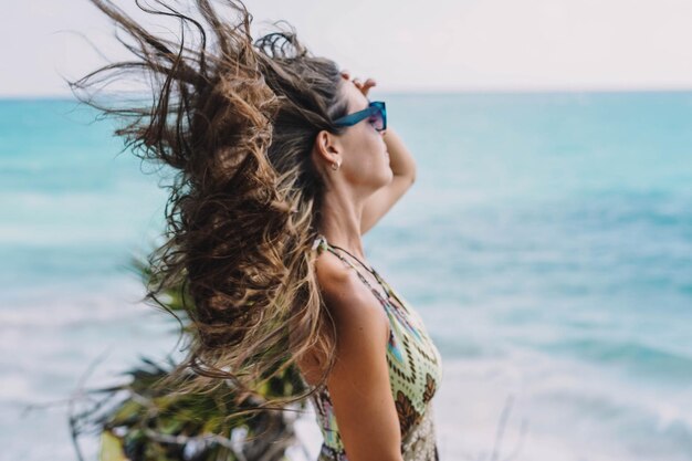 Donna in posa su una spiaggia con i capelli al vento