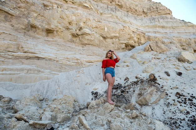 Donna in posa sullo sfondo di una montagna di sabbia, stile di vita estivo, bellezza della natura