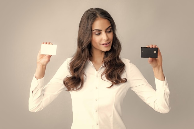 Donna in possesso di un modello di carta di credito bancaria con servizio online isolato su sfondo grigio Fortunata ragazza attraente che mostra il credito