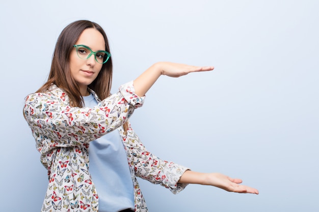 donna in possesso di un oggetto con entrambe le mani sul lato copia spazio, mostrando, offrendo o pubblicizzando un oggetto