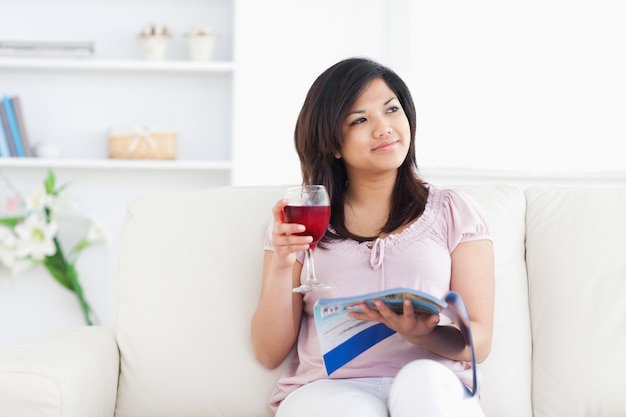 Donna in possesso di una rivista e un bicchiere di vino rosso