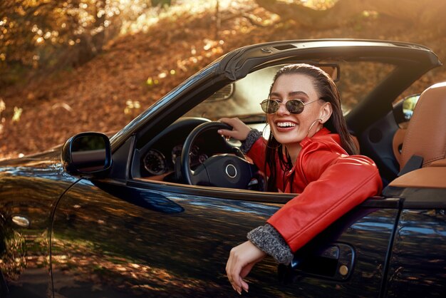 Donna in rosso in cabriolet indossa occhiali da sole