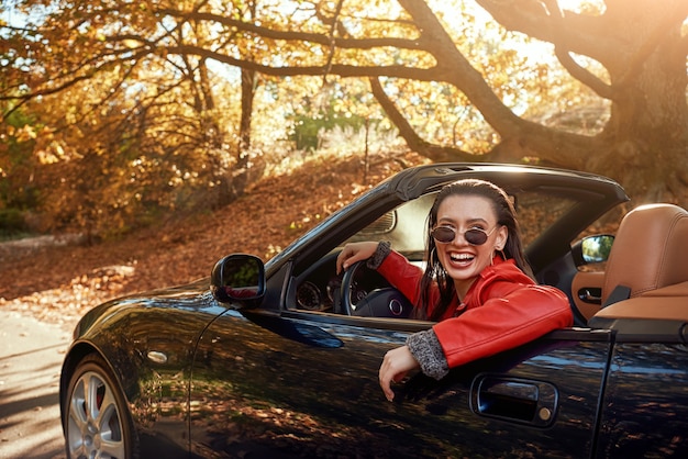 Donna in rosso in cabriolet indossa occhiali da sole