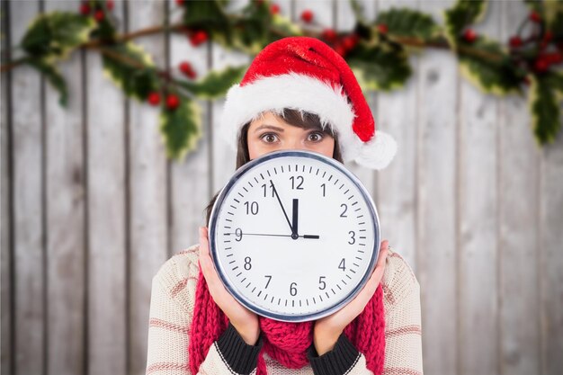 Donna in santa cappello in possesso di un orologio da parete su sfondo generato digitalmente