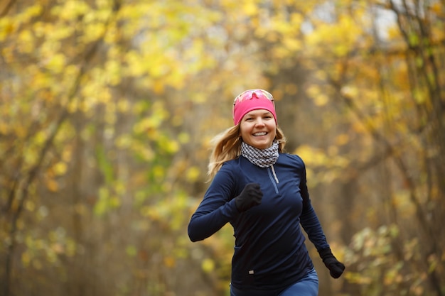 Donna in scarpe da ginnastica che corre tra le foglie d'autunno