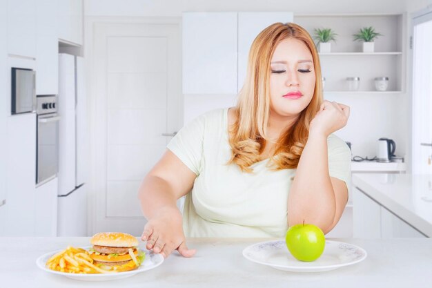 Donna in sovrappeso che rifiuta cibi veloci in cucina