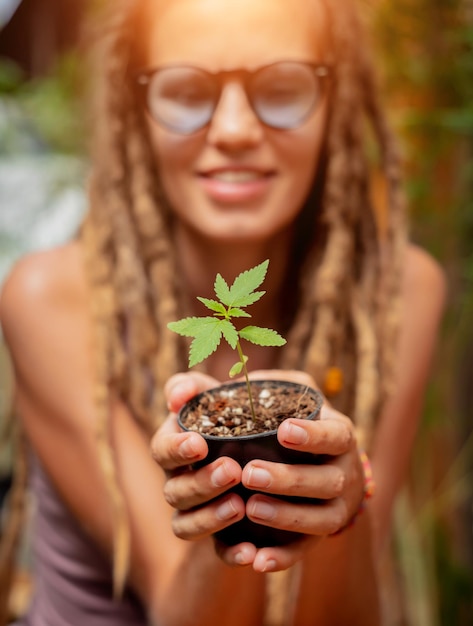 Donna in stile hippie che coltiva cespuglio di marijuana medica