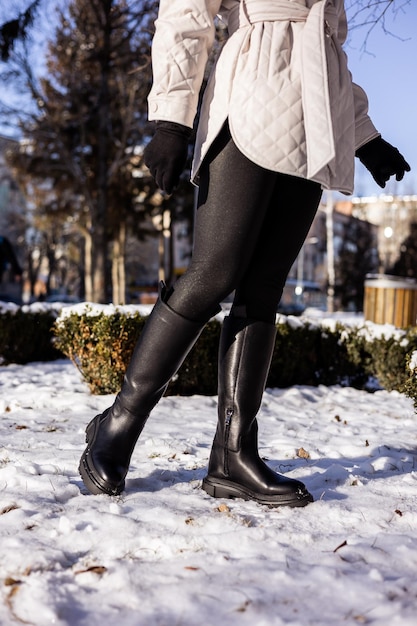 Donna in stivali neri alla moda su neve bianca primo piano Gambe da donna in eleganti stivali di pelle invernali