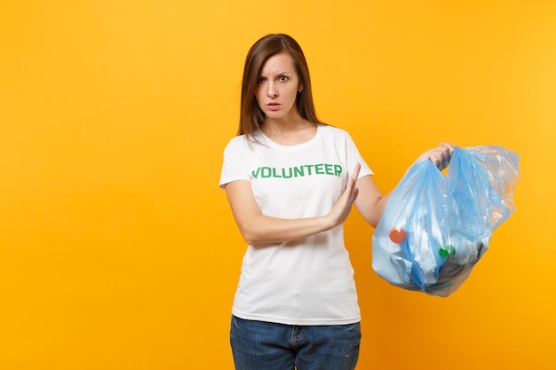 Donna in t-shirt volontaria, sacchetto della spazzatura isolato su sfondo giallo. Aiuto volontario gratuito, carità grazia. Problema di inquinamento ambientale. Arresti il concetto di protezione dell'ambiente dei rifiuti della natura.