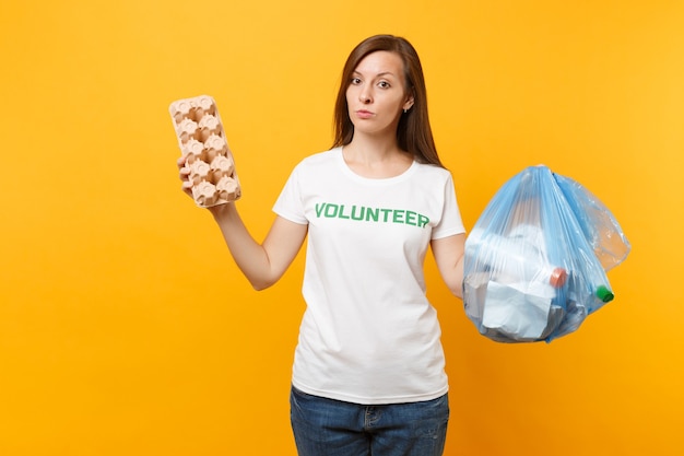 Donna in t-shirt volontaria, sacchetto della spazzatura isolato su sfondo giallo. Aiuto volontario gratuito, carità grazia. Problema di inquinamento ambientale. Arresti il concetto di protezione dell'ambiente dei rifiuti della natura.
