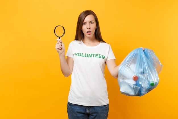 Donna in t-shirt volontaria, sacchetto della spazzatura isolato su sfondo giallo. Aiuto volontario gratuito, carità grazia. Problema di inquinamento ambientale. Arresti il concetto di protezione dell'ambiente dei rifiuti della natura.