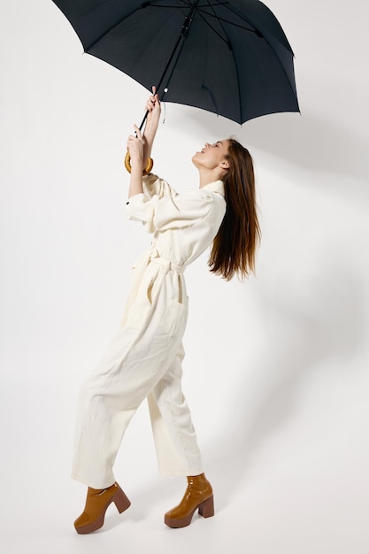 Donna in tuta bianca con protezione ombrello aperta dalla pioggia moda sfondo isolato