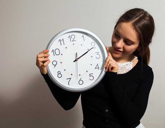 Donna in ufficio con grande orologio bianco