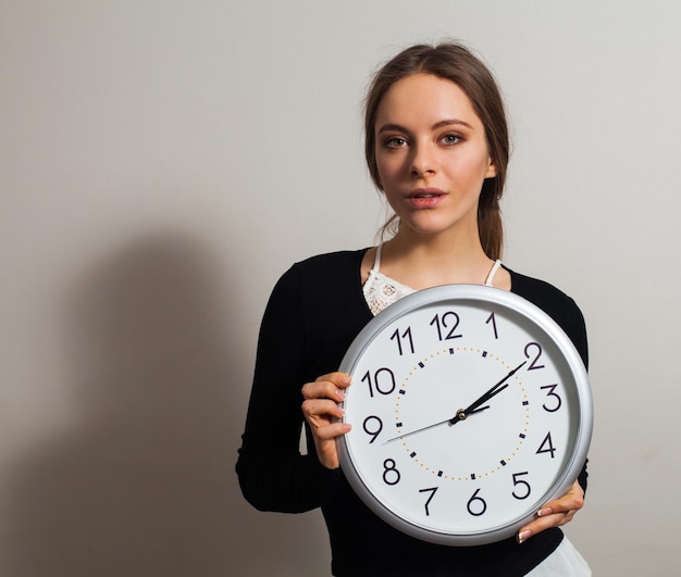 Donna in ufficio con grande orologio bianco