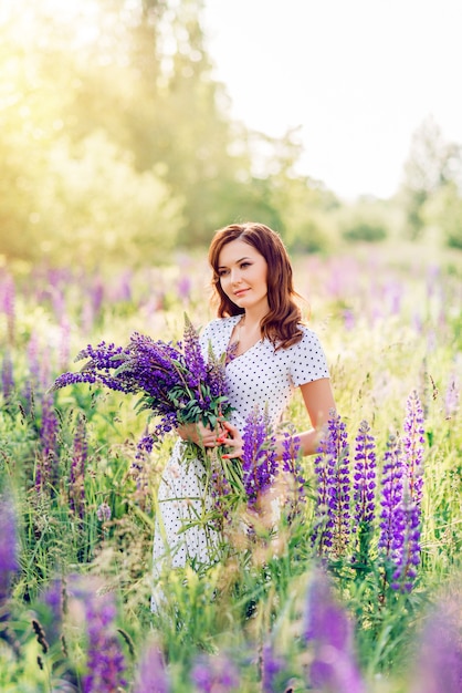 Donna in un campo con un mazzo di fiori selvatici