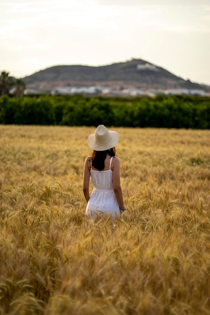 Donna in un campo di grano guardando la montagna