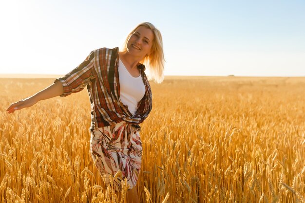 Donna in un campo di grano sullo sfondo del sole al tramonto