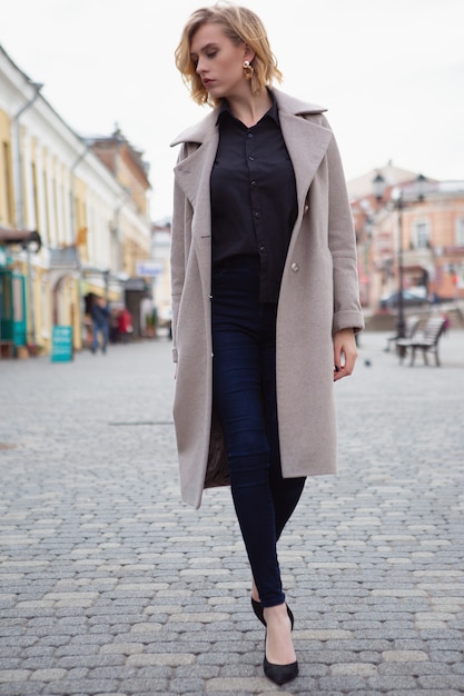 Donna in un cappotto che cammina per strada