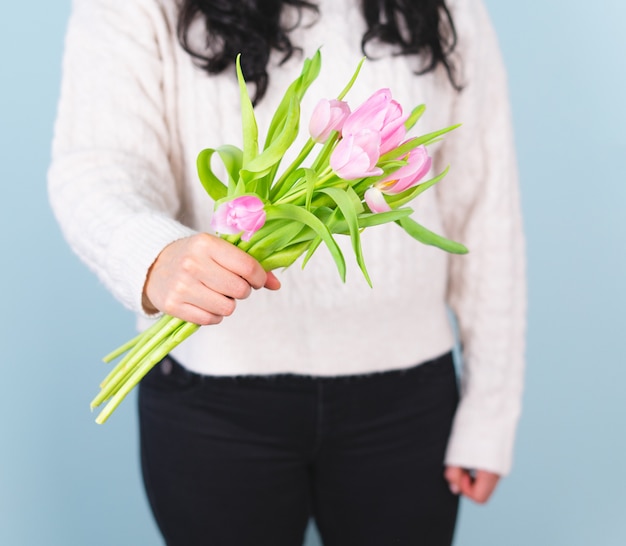 Donna in un maglione bianco con un mazzo di tulipani rosa. Concetto di primavera.