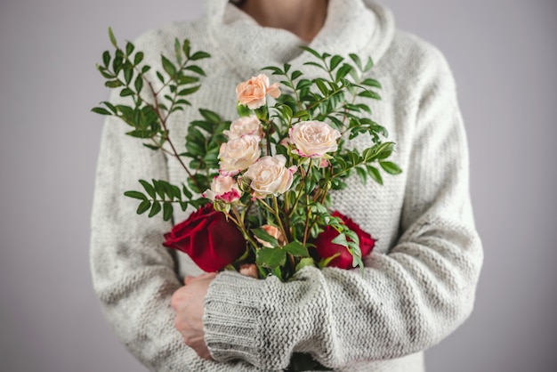 Donna in un maglione che tiene un mazzo di fiori di tenerezza