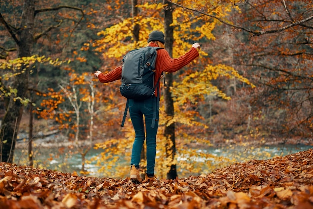 Donna in un maglione e jeans e stivali in autunno in un parco nella natura vicino al fiume